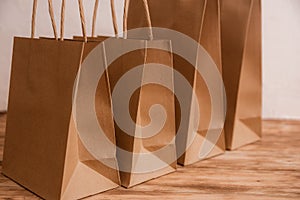 Mock-up of brown craft paper package with handles, empty shopping bag with area for your logo or design, wooden board in