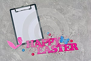 Mock up of clipboard with pink text of happy easter and bunny ears