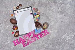 Mock up of clipboard with pink text of happy easter and chocolate traditional eggs