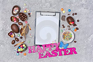 Mock up of clipboard with pink text of happy easter and chocolate traditional eggs