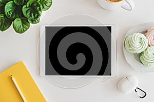 Mock-up digital tablet with empty screen, notebook, coffee cup, food and plant on white table. Top view. Flat lay