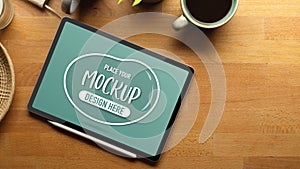 Mock up digital tablet on wooden table with copy space, coffee cup and supplies