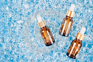 Mock up dropper bottles of facial anti aging serum with collagen and peptides on blue gel bubbles background with copy