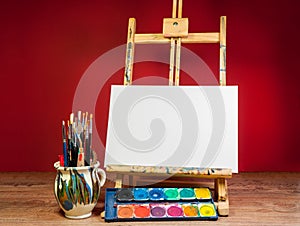 Mock up easel palette watercolors and brushes with empty white canvas