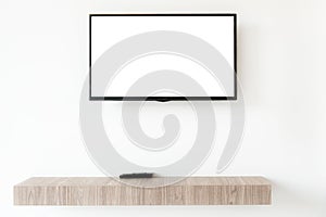 Mock up flat tv screen with remote panel on wwden shelf in living room at home.