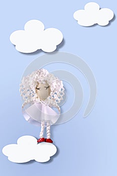 Mock up greeting card with cute handmade angel in white clothes on light blue background on white clouds.Copy space