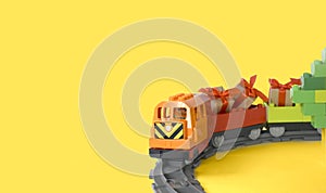 Mock up kids toys composition with colorful toy train with gifts on railway on yellow background.