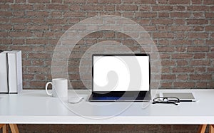 Mock up laptop computer, coffee cup, glasses and book on white table. Blank screen for your advertising text