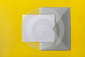 Mock-up letter or card with a silver envelope on a yellow background. Copy space.