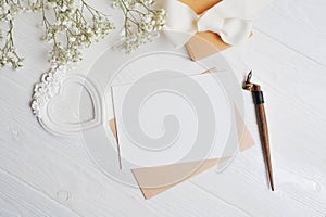 Mock up letter with a love box in the shape of a heart lies on a wooden white table with gypsophila flowers, a greeting card for V