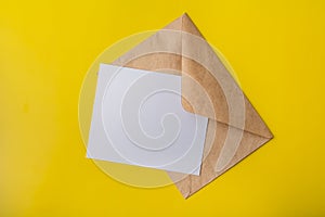 Mock-up letter or postcard with envelope from Kraft on a yellow background. Copy space.