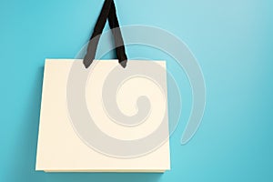 Mock up of light beige paper bag for fashion shopping on blue background with empty space