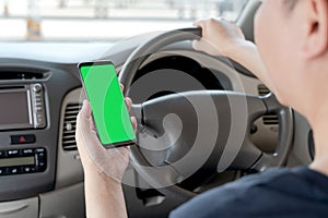 Mock up of man using mobile smart phone inside a car. Driver hand holding blank green screen smartphone, searching address and pin