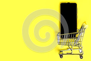 Mock up Mobile Phone Inside Shopping Cart or trolley on yellow background. Online Shopping ecommerce and food delivery fast