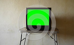 mock-up. Old tv with empty white screen for mockup stands on wooden table in room against vintage wallpaper. mock up. green