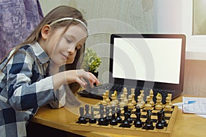 Mock-up online chess courses for children. Child with a chessboard and laptop. Little girl plays chess on the internet. Games for