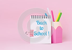 Mock up picture of notebook and office supplies, pencil holder on pink background.