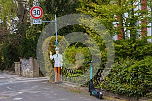 A mock-up of a police officer warns of a speed limit. Electric scooter in the foreground