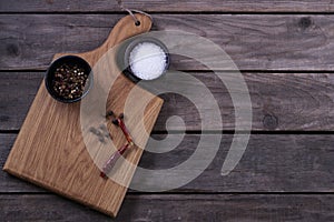 Mock up for restaraunt menu or recipe. Wooden cutting board with salt and pepper on the gray rustic background. Copy