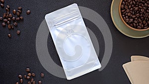 Mock-up, Roasted coffee beans in white plastic zipper bag and cup of coffee beans on black table leather.