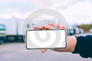 Mock up a smartphone in the hand of a man. Against the background of red trucks. Logistics concept