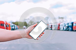 Mock up a smartphone in the hand of a man. Against the background of red trucks. Logistics concept.