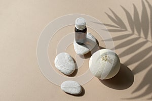 Mock up spa aromatherapy composition with bath bomb, essential oil bottle and pebbles on beige background.