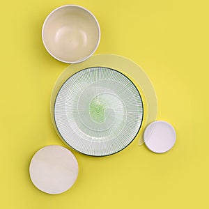 Mock up table setting on yellow background. Group of trendy ceramic utensil with plate, bowl and sauser