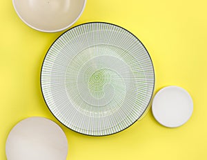 Mock up table setting on yellow background. Group of trendy ceramic utensil with plate, bowl and sauser for summer serving or rest photo