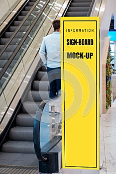Mock up tall signboard near escalator in shopping mall