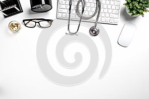 Mock up of white doctors desk with stethoscope, keyboard, mouse, glass and pen.Top view with copy space