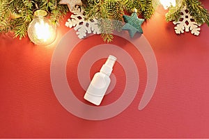 Mock-up of white plastic spray bottle, Christmas fir tree and Christmas decorations on a red background. Top view, flat lay style