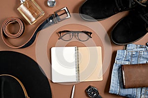 Mock up workspace with hat, clock, pen, perfume, jeans, purse, belt, footwear, notepad and eyeglasses on brown background.