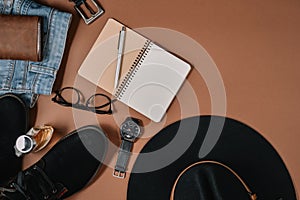 Mock up workspace with hat, clock, pen, perfume, jeans, purse, belt, footwear, notepad and eyeglasses on brown background. Concept