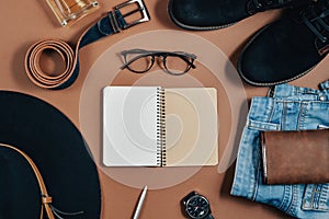 Mock up workspace with hat, clock, pen, perfume, jeans, purse, belt, footwear, notepad and eyeglasses on brown background. Concept