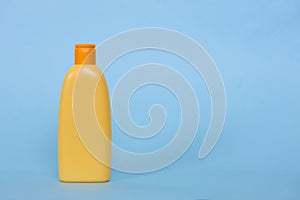 Mock up of a yellow plastic bottle with a cosmetic liquid product on a blue background. Space for logo