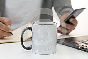 Mockup of 11oz white ceramic mug with black handle with copy space for your design. Businessman working on background