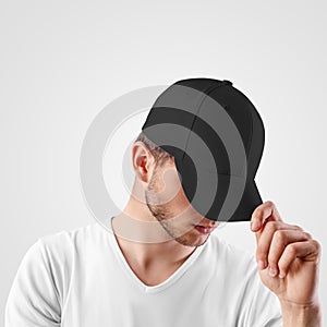 Mockup of a black baseball cap on a guy`s head, looking from under a visor, front view, empty panama for design presentation