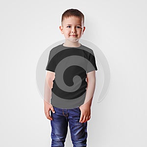Mockup of black childrens t-shirt on a boy in blue jeans, isolated on background