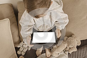 Mockup of black digital tablet pc with blank white screen in hands of little boy. Child using tablet computer at home