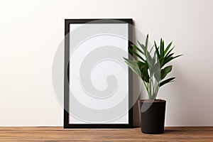 Mockup of black vertical frame with white blank card and potted plant. Minimalistic frame mockup poster on floor leaning