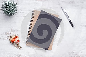 Mockup blank black book cover with pen, Christmas ornaments decor on white grunge wooden table background. Flat lay, Top view with