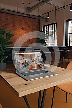 Mockup blank screen laptop on wood table in co-working space.