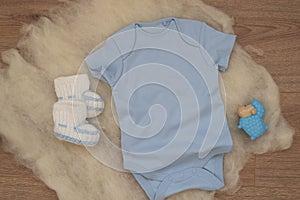 Mockup of blue baby bodysuit on wood background. Blank baby clothes template mock up. Flat lay styled stock photo