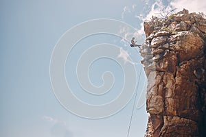 Mockup blue sky, mountain climbing woman and rock wall fearless hiking on abseiling training rope outdoor. Healthy