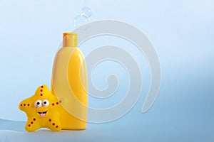 Mockup bottle of baby washing gel, bath foam, liquid soap or shampoo with yellow star fish and flying soap bubbles