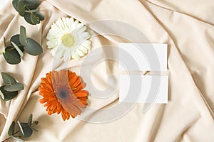 Mockup business card with eucalyptus leaves, gerbera and nude fabric