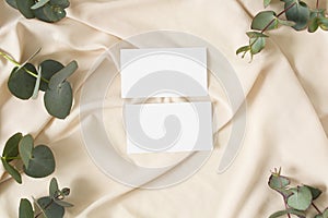 Mockup business card with eucalyptus leaves, gerbera and nude fabric