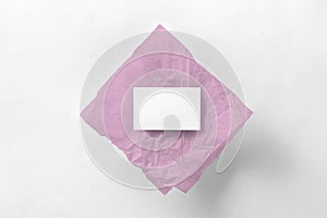 Mockup of business card on pink tracing paper at white textured