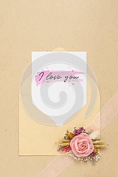 Mockup card and envelop on white wood with I love you text and kraft roses for Valentine`s Day. Mock up for elegant design. Flat